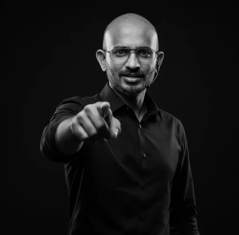 Zammy Zaif pointing towards the camera, wearing a headset microphone